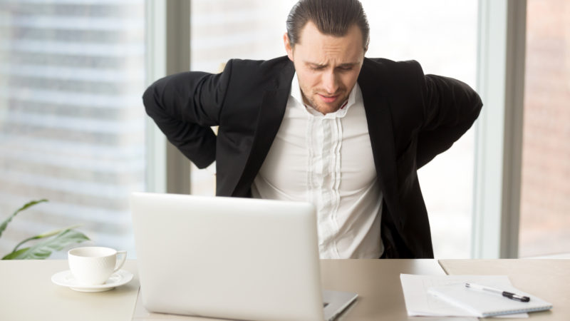 Businessman suffering from backache at workplace